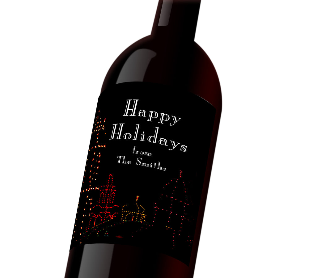 A black holiday customizable wine label with the plaza outlined in holiday lights. The label reads, "Happy Holidays from The Smiths"