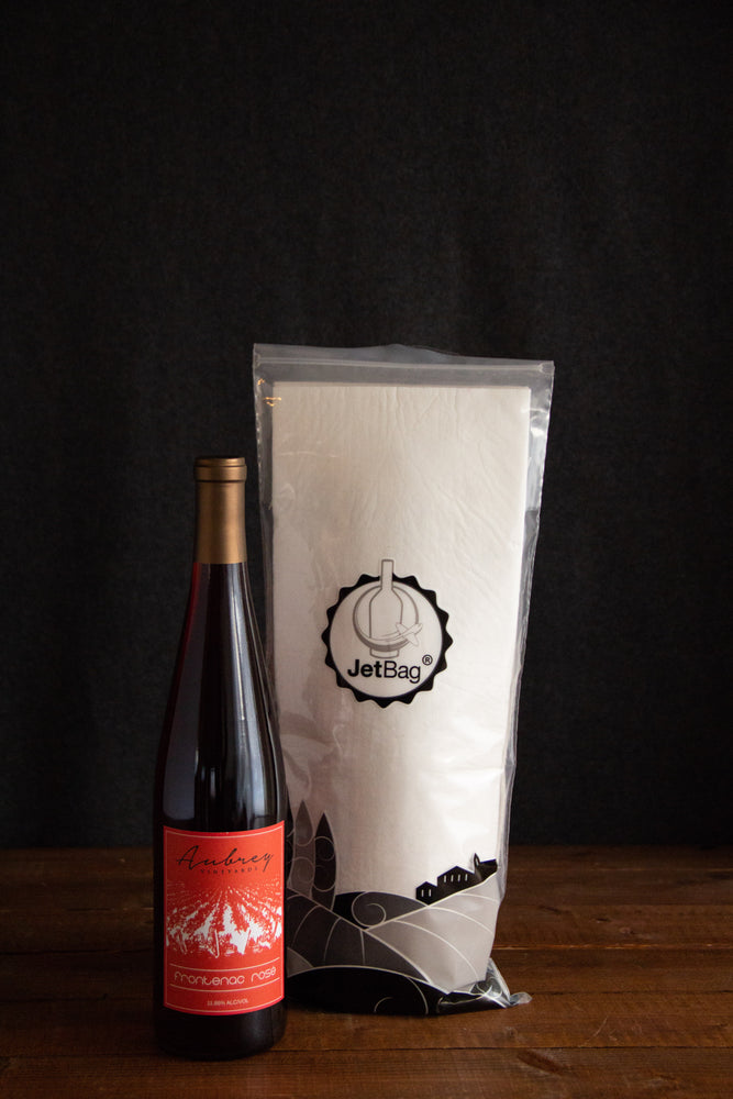 
                  
                    Load image into Gallery viewer, A JetBag used to protect your wine while traveling sitting behind a bottle of Aubrey Vineyards Frontenac Rosé.
                  
                
