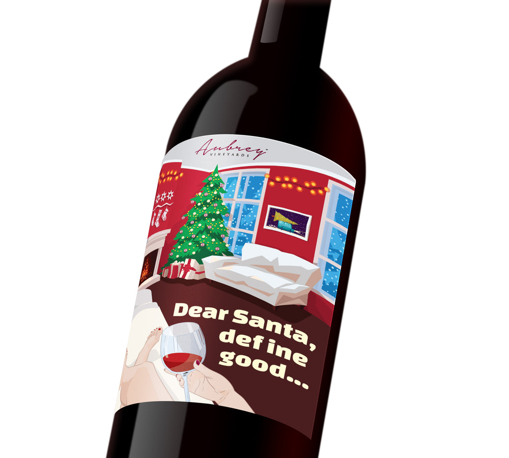A holiday wine label with the illustration of a woman sitting on the couch, glass of wine in hand, looking at her Christmas tree. The label reads, 