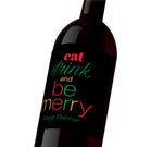A black holiday wine label with red, green, and yellow text that reads, "Eat, drink, and be merry. Happy Holidays"